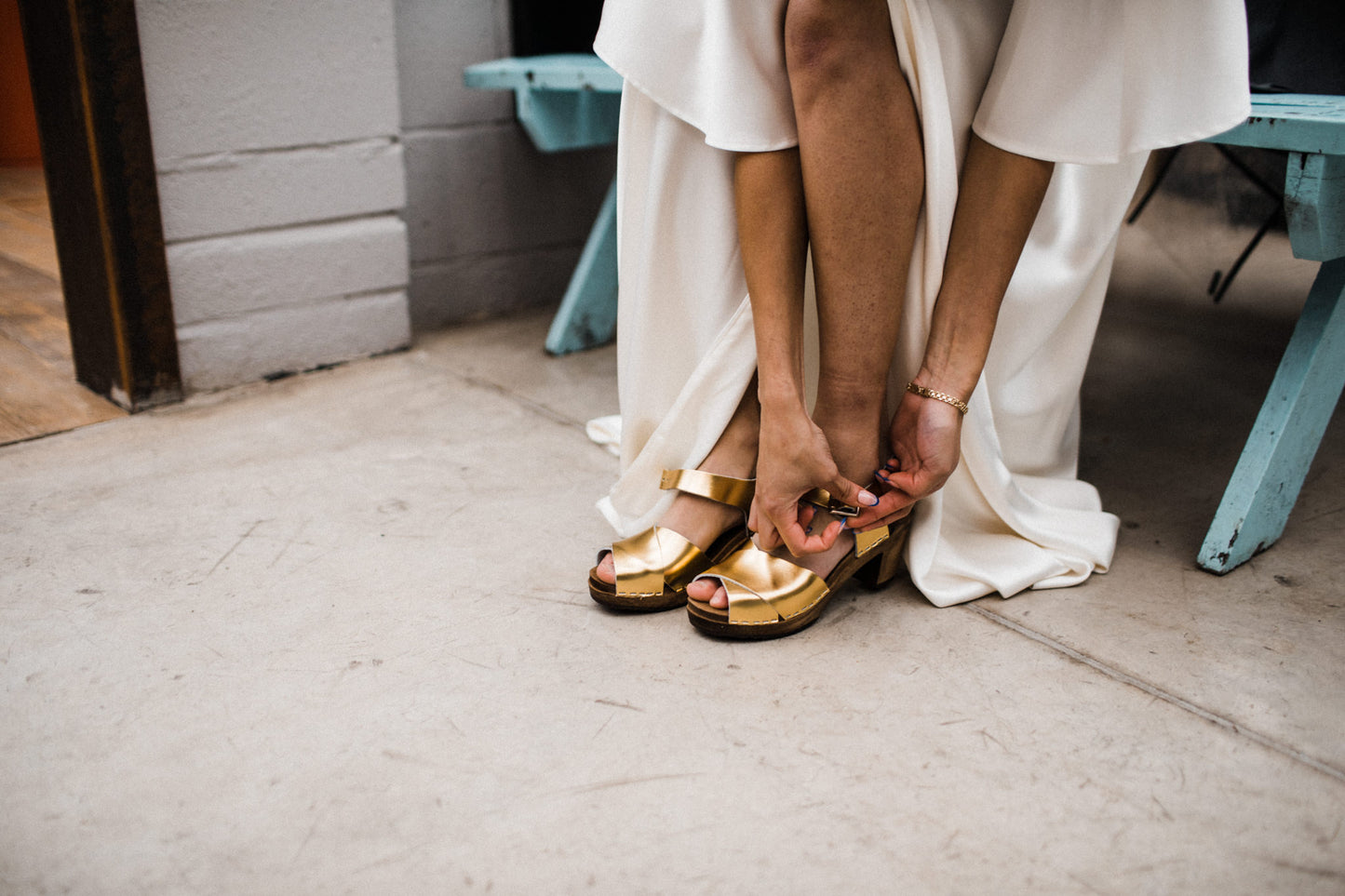 Gold metallic cross over sandal clog with ankle strap and a mid heel bridal